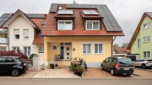 A residential building with solar panels, a front entrance, and a driveway with parked cars. - Apartment 'Ferienwohnung Glöckler' with Shared Garden and Wi-Fi (Freiburg im Breisgau)