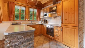A kitchen with wooden cabinets, a stone island, and a built-in oven. - Holiday Home 'Hexenhäuschen' with Mountain View, Private Terrace and Wi-Fi (Wolfach)