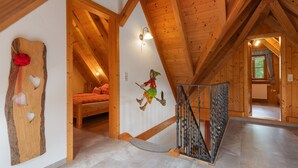A wooden interior with a sloped ceiling, a staircase, a bed, and a wall with a whimsical painting. - Holiday Home 'Hexenhäuschen' with Mountain View, Private Terrace and Wi-Fi (Wolfach)