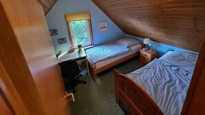 Ein Schlafzimmer mit zwei Betten, einem Schreibtisch und einem Fenster.