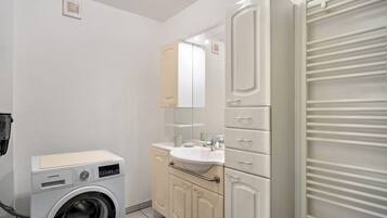 Een kleine badkamer met een wasmachine, een wastafel en een spiegel.