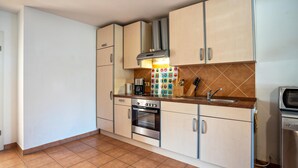 A kitchen with white cabinets, a stove, oven, microwave, and a sink. - Apartment 'Reinhards' with Private Terrace, Private Garden and Wi-Fi (Greifswald)