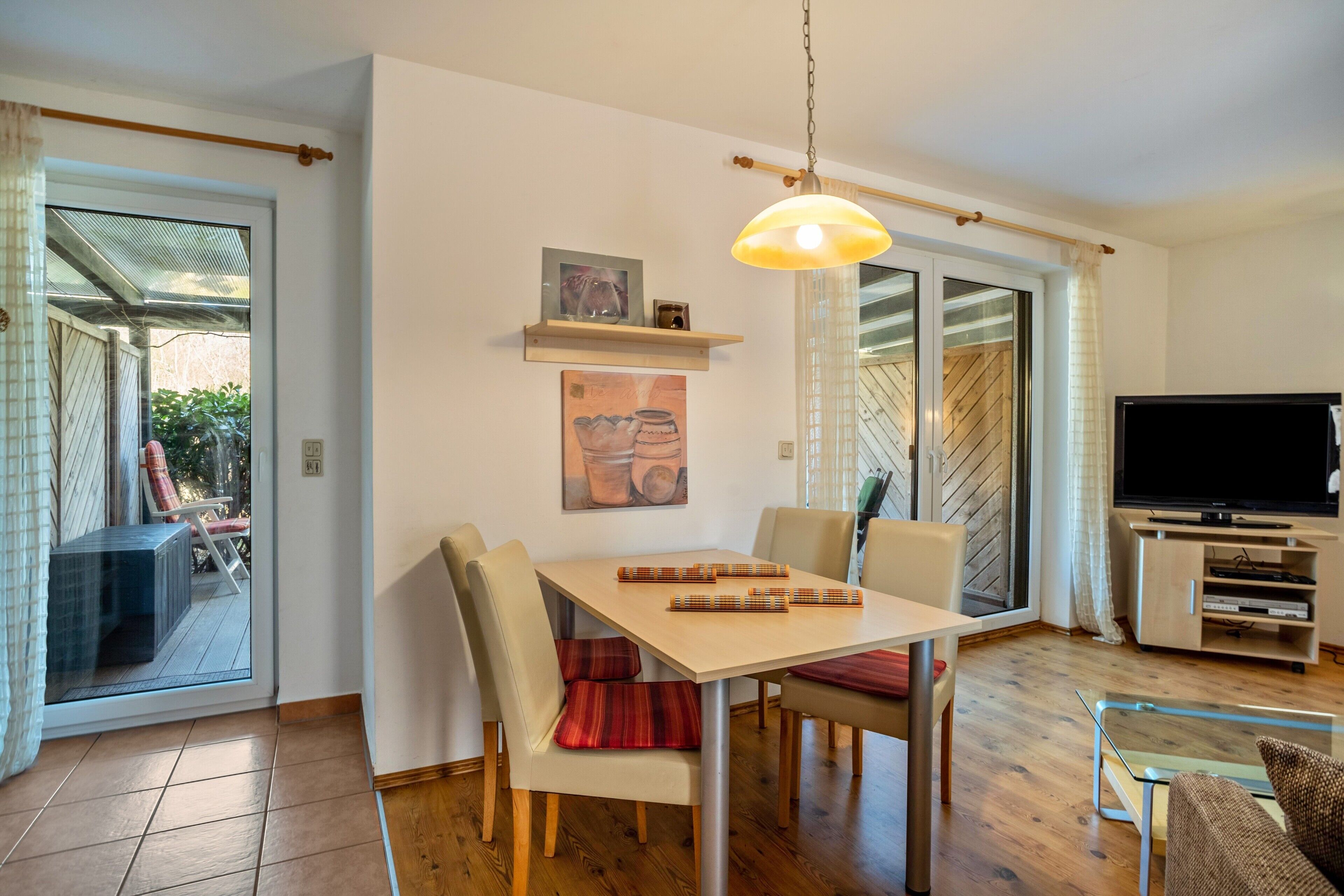 A dining area with a table, chairs, and a hanging light fixture.