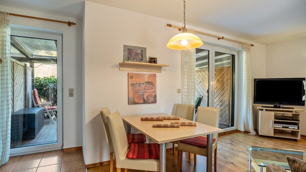 A dining area with a table, chairs, and a hanging light fixture. - Apartment 'Reinhards' with Private Terrace, Private Garden and Wi-Fi (Greifswald)