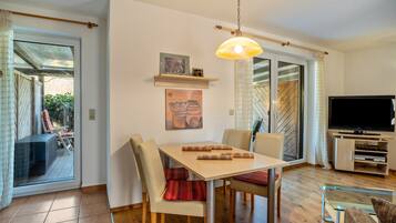 A dining area with a table, chairs, and a hanging light fixture.
