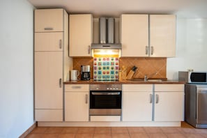 A kitchen with light-colored cabinets, a stainless steel oven, a microwave, and a coffee maker. - Apartment 'Reinhards' with Private Terrace, Private Garden and Wi-Fi (Greifswald)