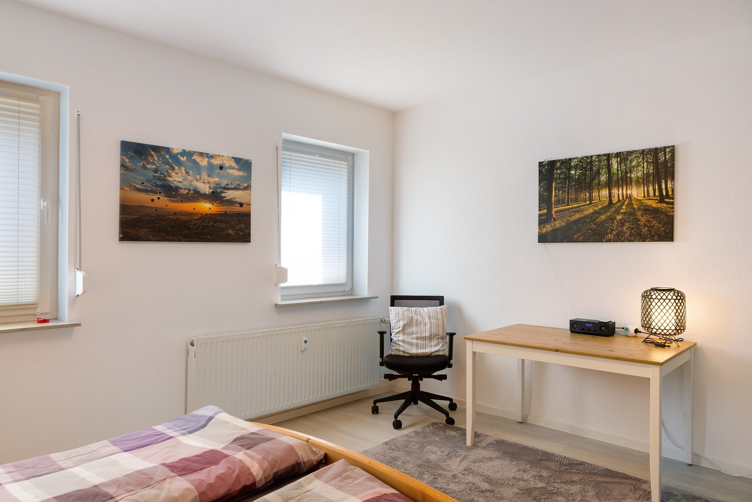 Ein Schlafzimmer mit einem Bett, einem Schreibtisch und zwei Bildern an der Wand.