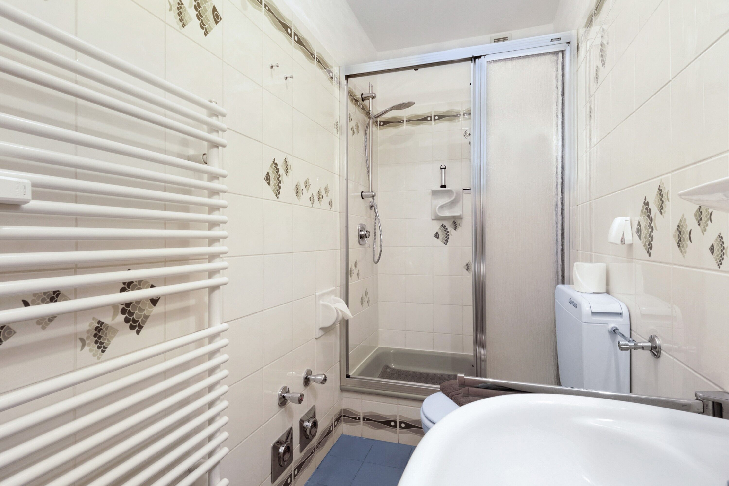 Baño con ducha, inodoro y perchero para toallas.