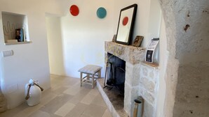 A cozy room with a stone fireplace, a wooden bench, and a small stool. - TD Trulli Dell Uliveto Cozy Trulli With Pool (Castellana Grotte)