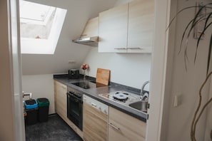 A compact kitchen with a skylight, built-in oven, dishwasher, and a small countertop.