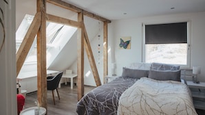 Une chambre à coucher comprenant un lit, un bureau et une chaise, avec une lucarne et une fenêtre.