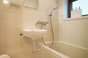 A bathroom with a white sink, a shower, and a window above the bathtub. - Penthouse 1-bedroom Flat in Hiroo Shibuya (Tokyo)