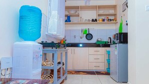 Una cocina compacta con dispensador de agua, refrigerador y microondas.