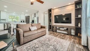 A modern living room with a sofa, a TV, and a fireplace.