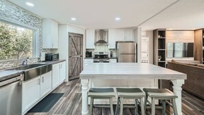 A modern kitchen with a large island, stainless steel appliances, and a view of the outdoors.