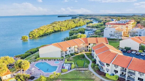 Un resort con piscina, vista a la playa y varios edificios con techos rojos.