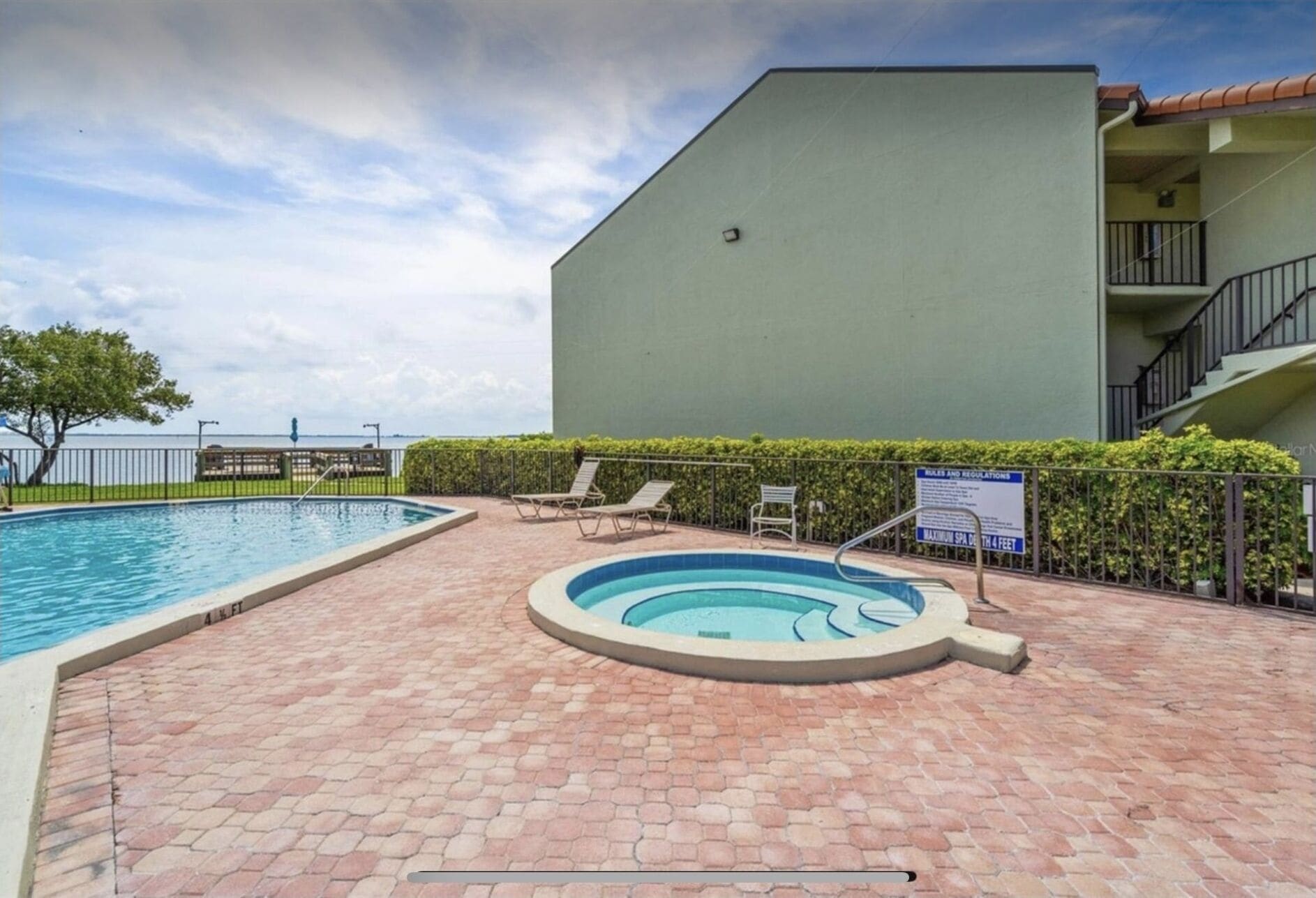 Une piscine avec un jacuzzi, des chaises longues et un panneau indiquant une profondeur de 1,2 mètre (4 pieds).