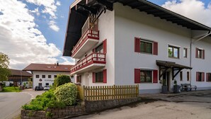 A two-story building with a balcony, a wooden fence, and a bench. - Ferienwohnung Chiemsee 72 qm (Rimsting)