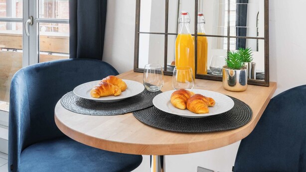 A dining area with a table, chairs, a mirror, and a bottle of orange juice.