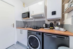 A compact kitchen with a washing machine, microwave, and coffee maker.