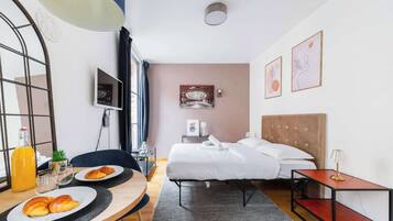 Une chambre d’hôtel équipée d’un lit, d’une table de chevet, d’une lampe, d’œuvres d’art et d’un plateau de petit-déjeuner.