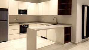Una cocina moderna con una isla central, electrodomésticos integrados y estantes de madera.