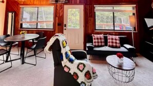 A cozy room with a high ceiling, wooden walls, a dining area, and a seating area with a couch and a coffee table. - Unique/modern/Mt Si/Shopping (North Bend)