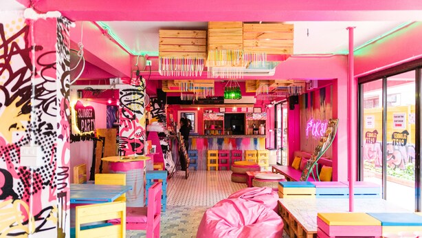 A vibrant, colorful interior with a central seating area, wooden tables, and a neon sign. - Slumber Party Chiang Mai (Chiang Mai)