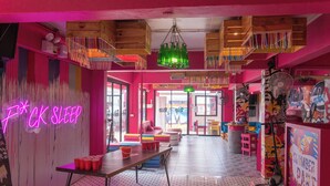 A vibrant room with a neon sign, wooden furniture, and a colorful wall design. - Slumber Party Chiang Mai (Chiang Mai)