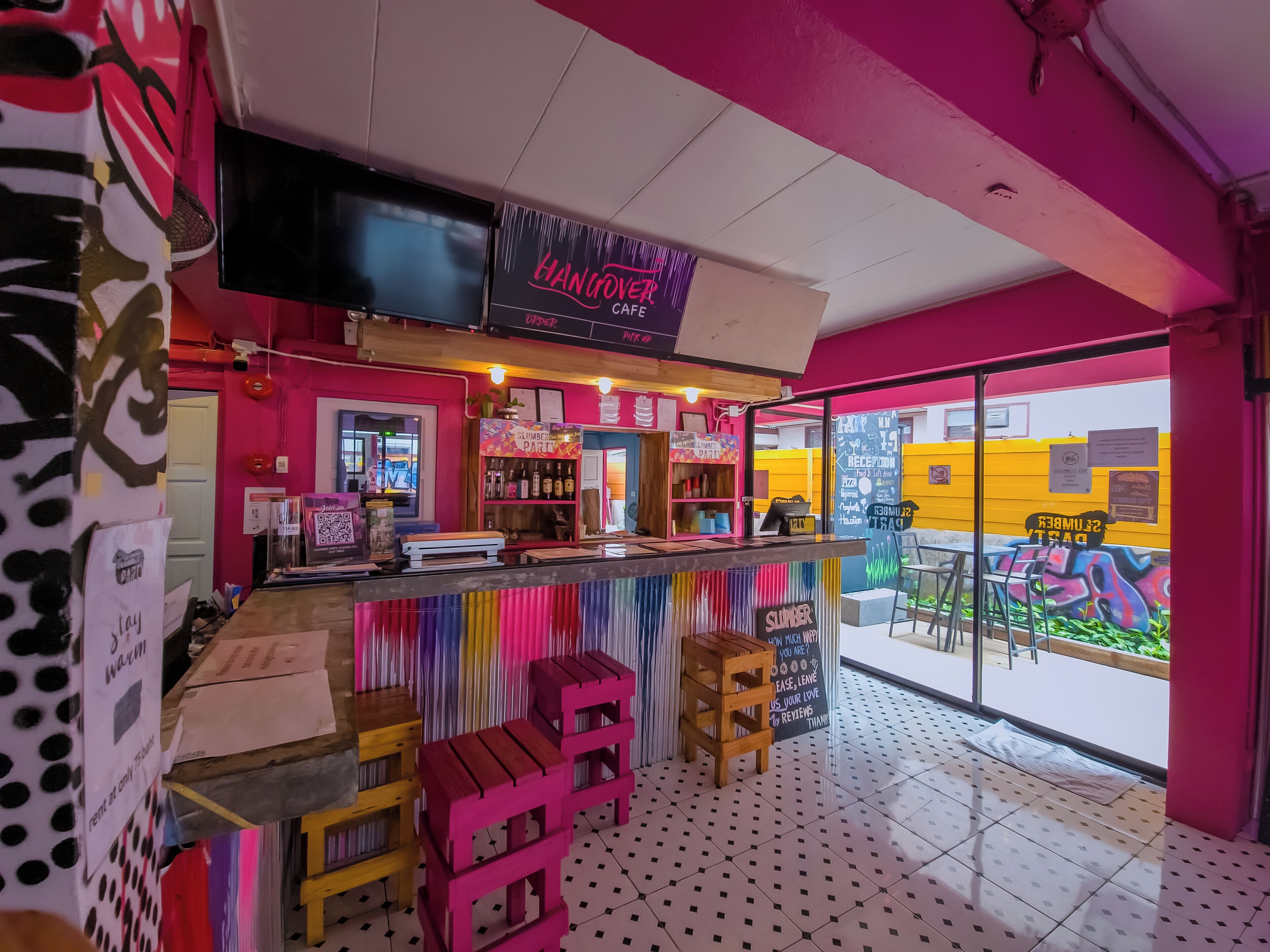 A vibrant café interior with a counter, stools, and a large window offering an outdoor view.