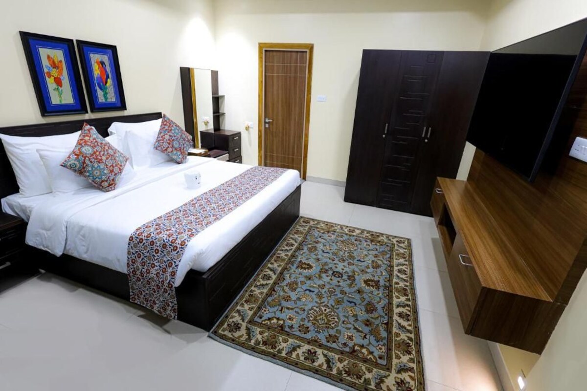 A bedroom with a bed, a TV, a wardrobe, and a rug.