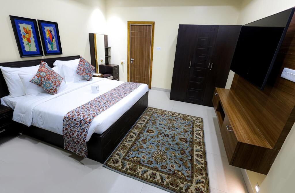 Un dormitorio con cama, televisor, armario y alfombra.