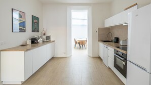 A modern kitchen with white cabinets, a wooden countertop, a built-in oven, and a view to a dining area. - Le Windsor avec extérieur, pour un plaisir partagé (Cannes)
