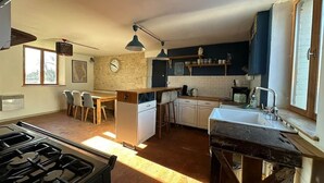 Una cocina compacta con estufa a gas, un lavamanos y una zona de comedor con sillas.