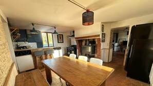 Una cocina con una mesa de comedor, sillas, una lámpara colgante y una chimenea de ladrillo.