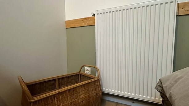 Ein Zimmer mit Holzboden, weißem Heizkörper und einem Korbwannenkorb.