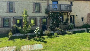 Ein zweistöckiges Gebäude mit Balkon, Backsteinwänden und einem kleinen Garten.