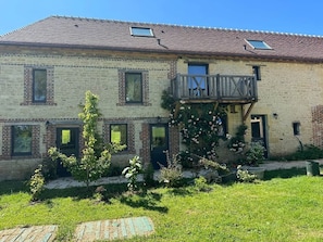 En toetagers bygning med balkon, murstensvægge og en lille have.