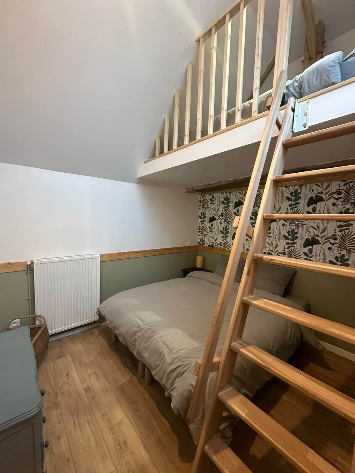 A bunk bed room with a wooden ladder, a radiator, and a small bedside table.
