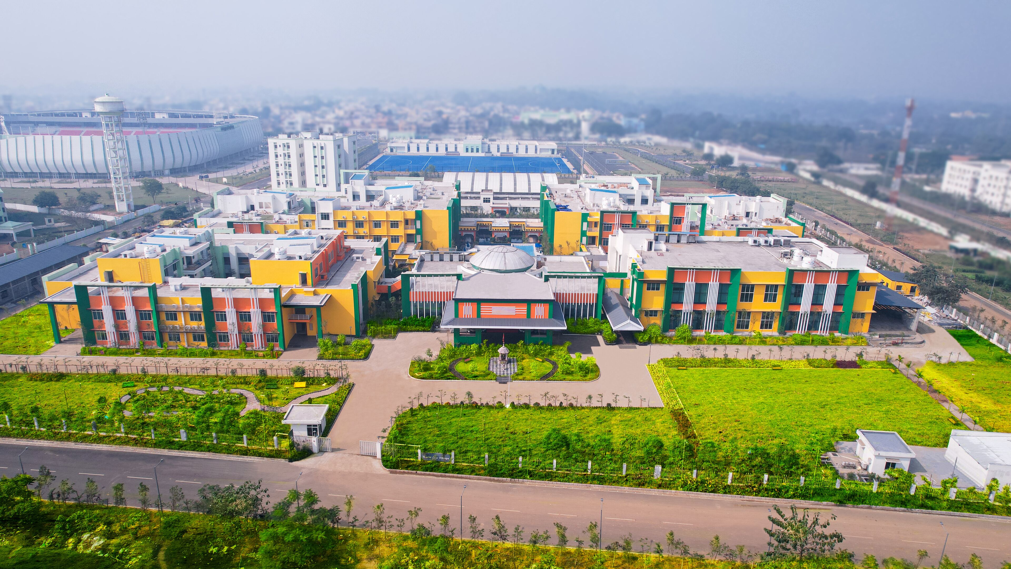 A large, multi-story building with a central courtyard and surrounding greenery.