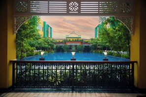 A view from a balcony with a pool, surrounded by ornate railings and lush greenery. - Mayfair World Cup Village (Rourkela)