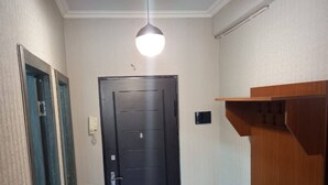 A hallway with a black door, a light fixture, and a wooden bench. - Best Location, Cozy Spacious Apart Near Republic (Yerevan)