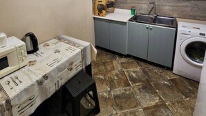 A compact kitchen with grey cabinets, a washing machine, a microwave, and a table set for dining. - Best Location, Cozy Spacious Apart Near Republic (Yerevan)