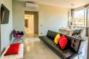 A modern living room with a sofa, a chair, and a dining area with a table and chairs.