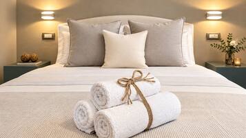 A neatly made bed with pillows, a bedside table with a lamp, and a vase with flowers.