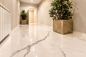 A hallway with a polished marble floor, a potted plant, and a radiator. - Signature Design & Panoramic Views in the heart of Montecatini Terme (Montecatini Terme)