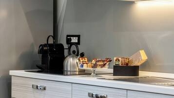 Angolo cottura accessoriato con macchina da caffè, bollitore e portacapsule.
