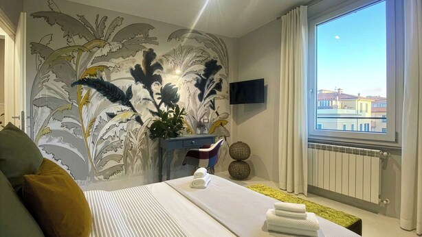 Habitación de hotel con cama, escritorio, silla, televisor y ventana con vistas.
