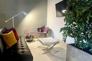 A modern living room with a sofa, a chair, a small table, a floor lamp, and a large potted plant. - Signature Design & Panoramic Views | Montecatini Terme (Montecatini Terme)