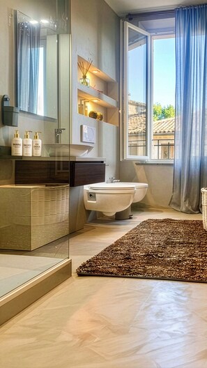 A modern bathroom with a glass shower enclosure, a toilet, and a sink area with toiletries. - Signature Design & Panoramic Views in the heart of Montecatini Terme (Montecatini Terme)